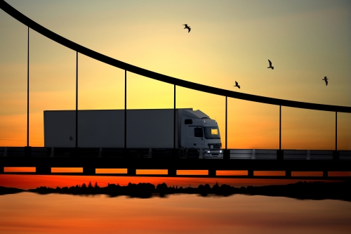 Semi truck crossing bridge in front of sunset